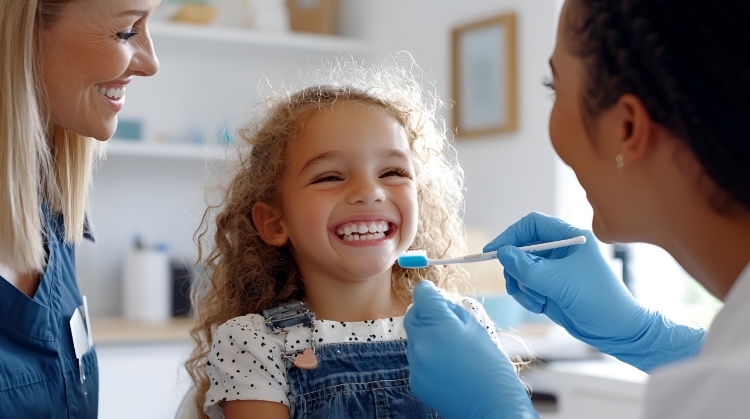 Happy child smiling during dental visit with dentist and parent nearby.